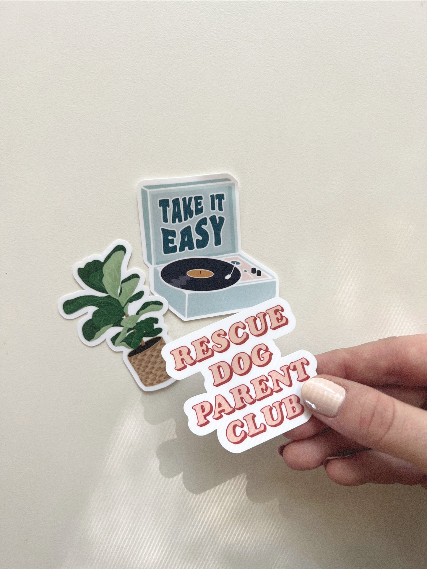 3 stickers - One saying "Rescue Dog Parent Club", one record player saying "Take it Easy" in wavy retro text, and an illustrated fiddle leaf fig