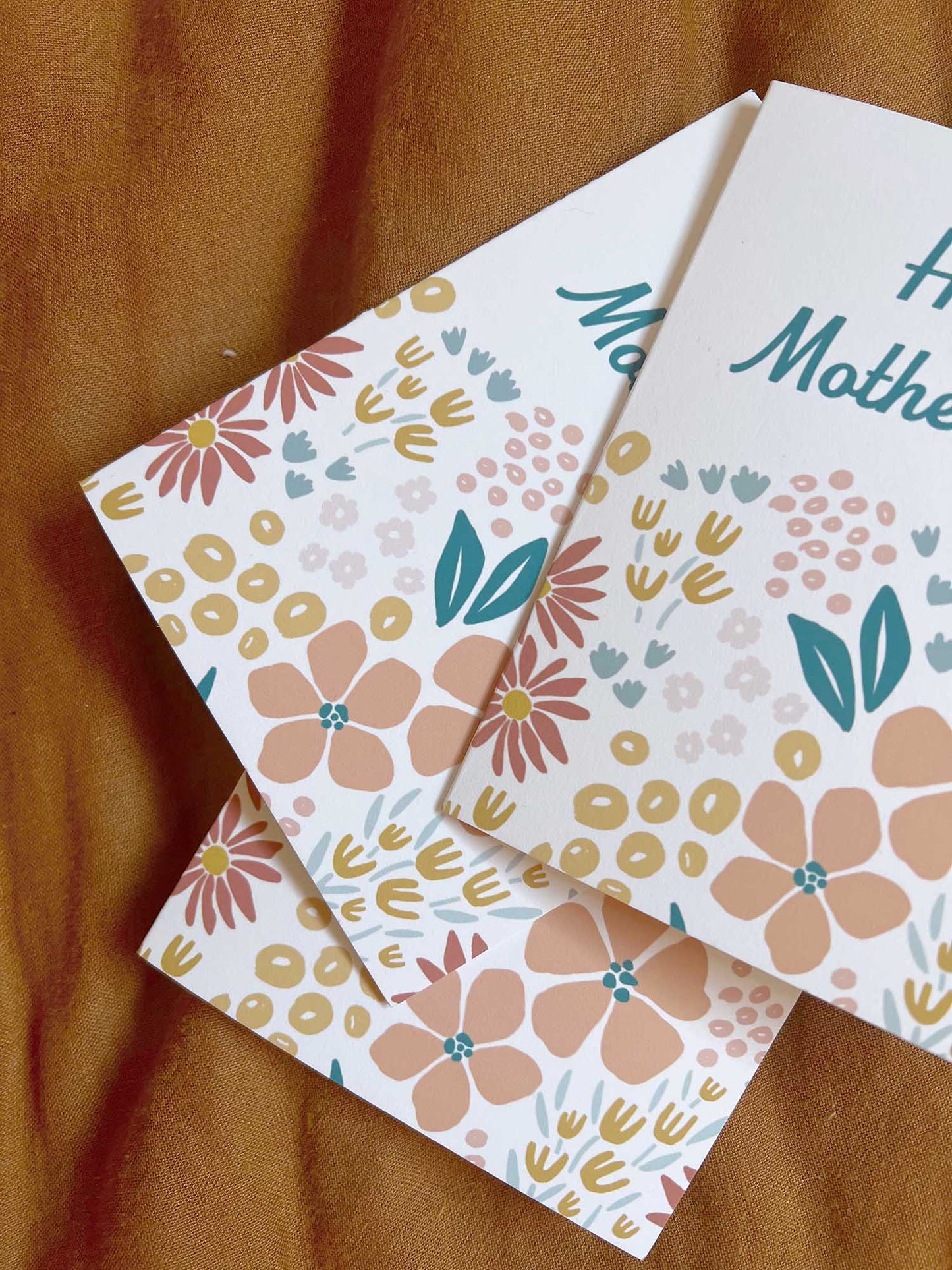 Multiple Floral Mother's Day cards on a rust fabric background