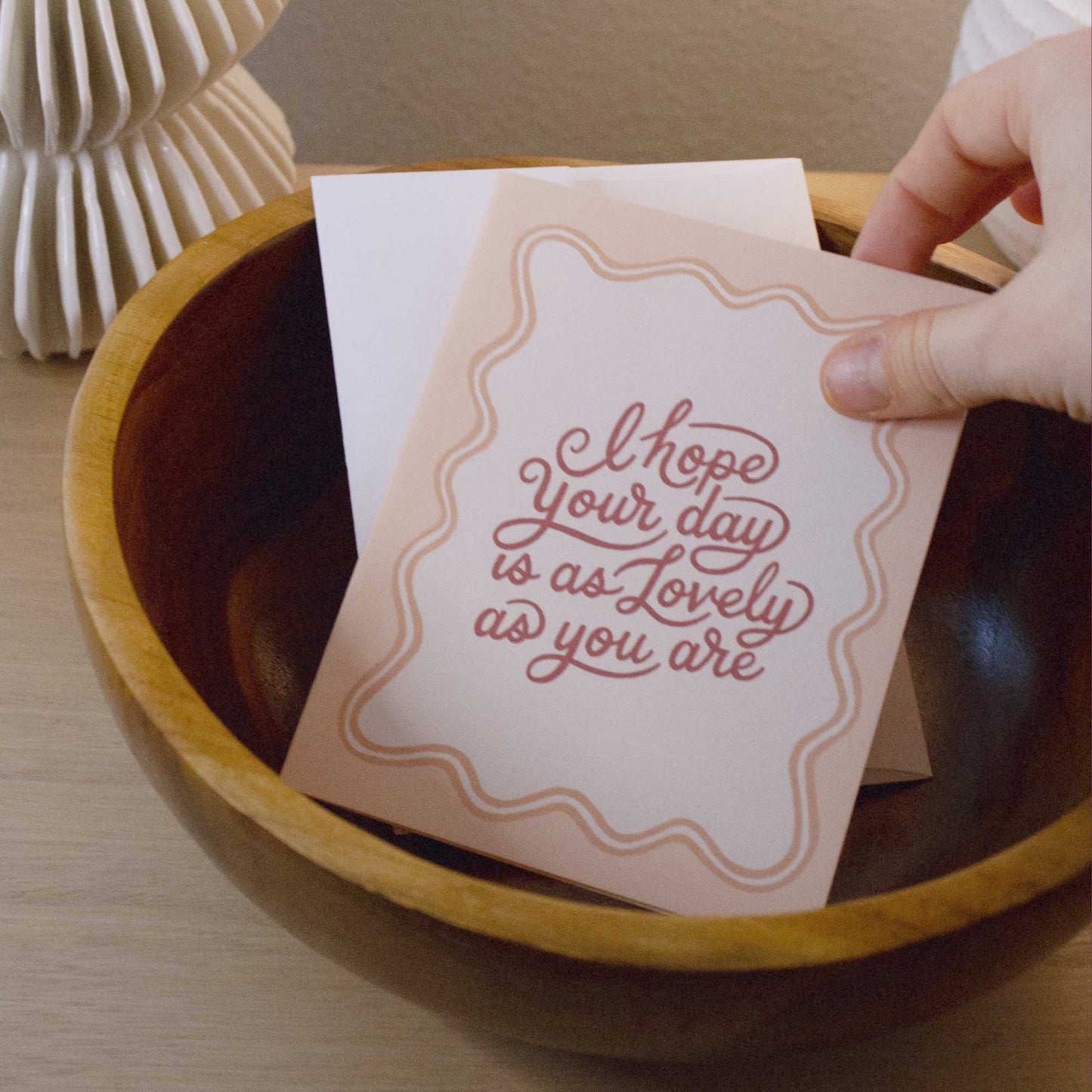 "I hope your day is as lovely as you are" card in a teak bowl with a white, ribbed CB2 vase