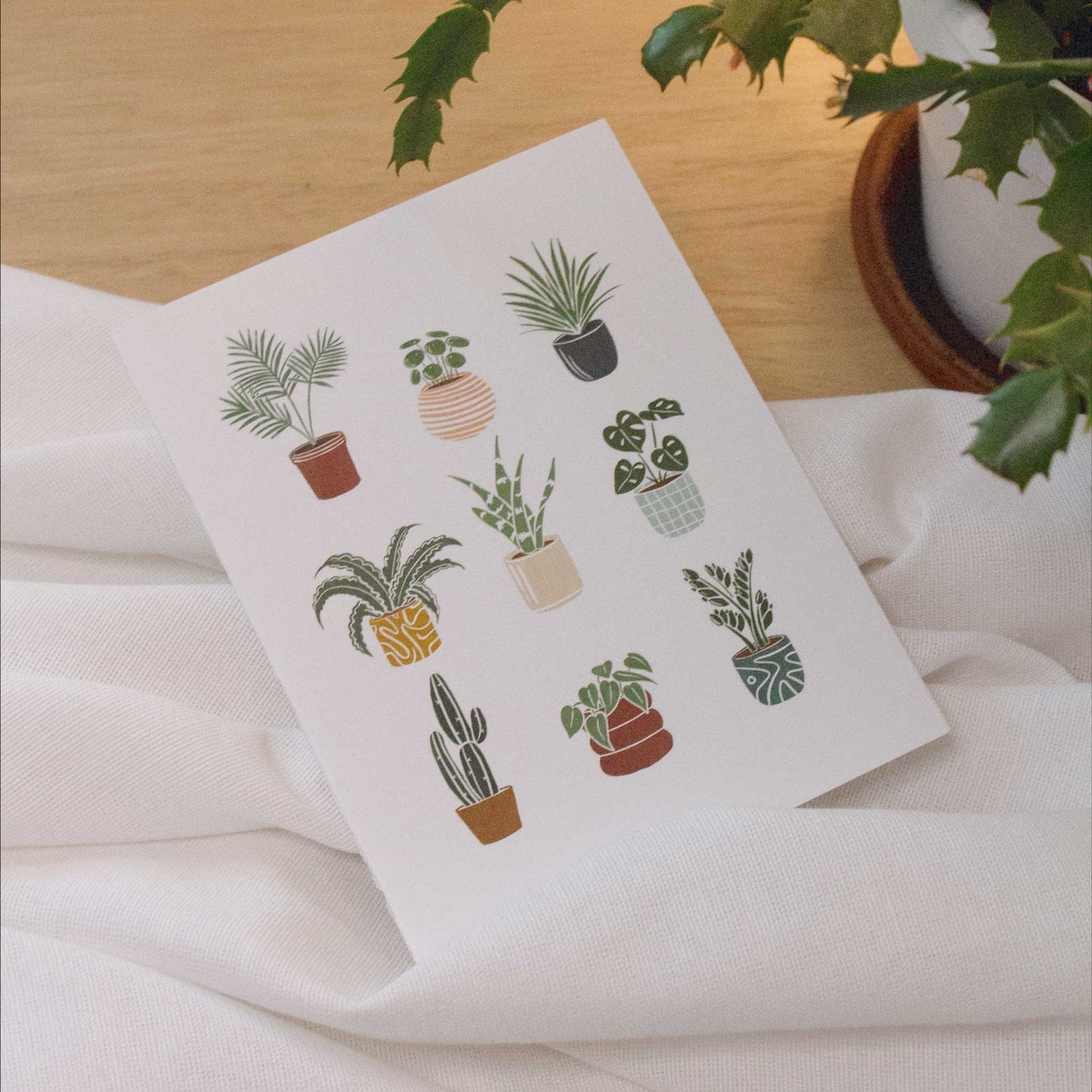 Plants greeting card on white fabric on a light wood background next to a cactus