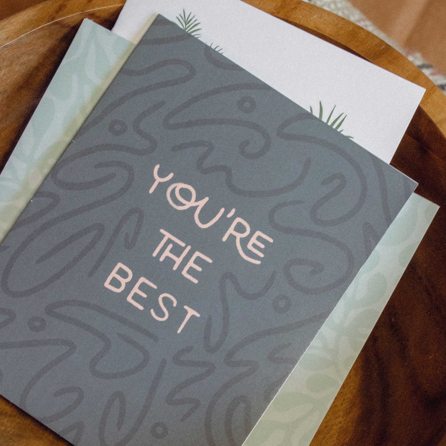 Mixed card pack in a teak bowl on a southwestern embroidered pillow