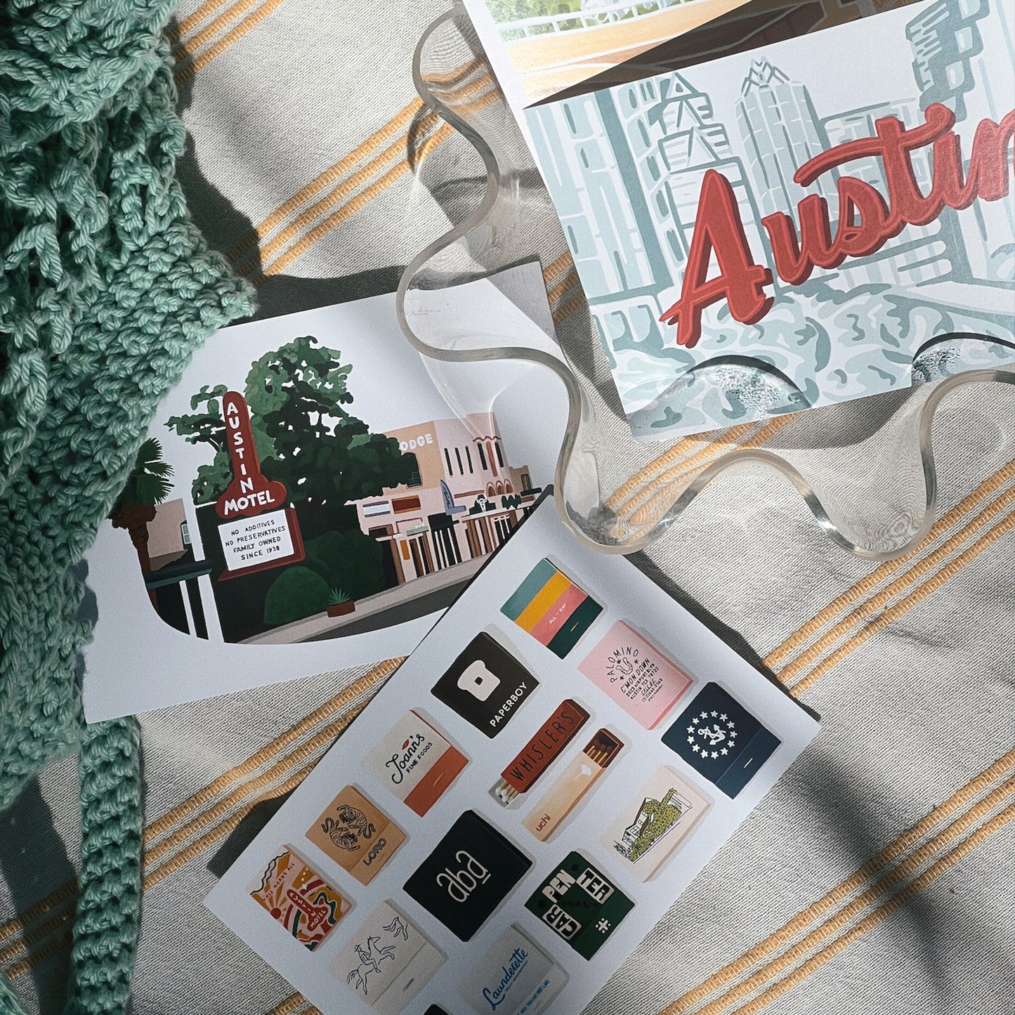 4 austin texas themed postcards depicting south congress, austin motel, the ATX skyline, lady bird lake, and matchbooks from Austin's most popular restaurants