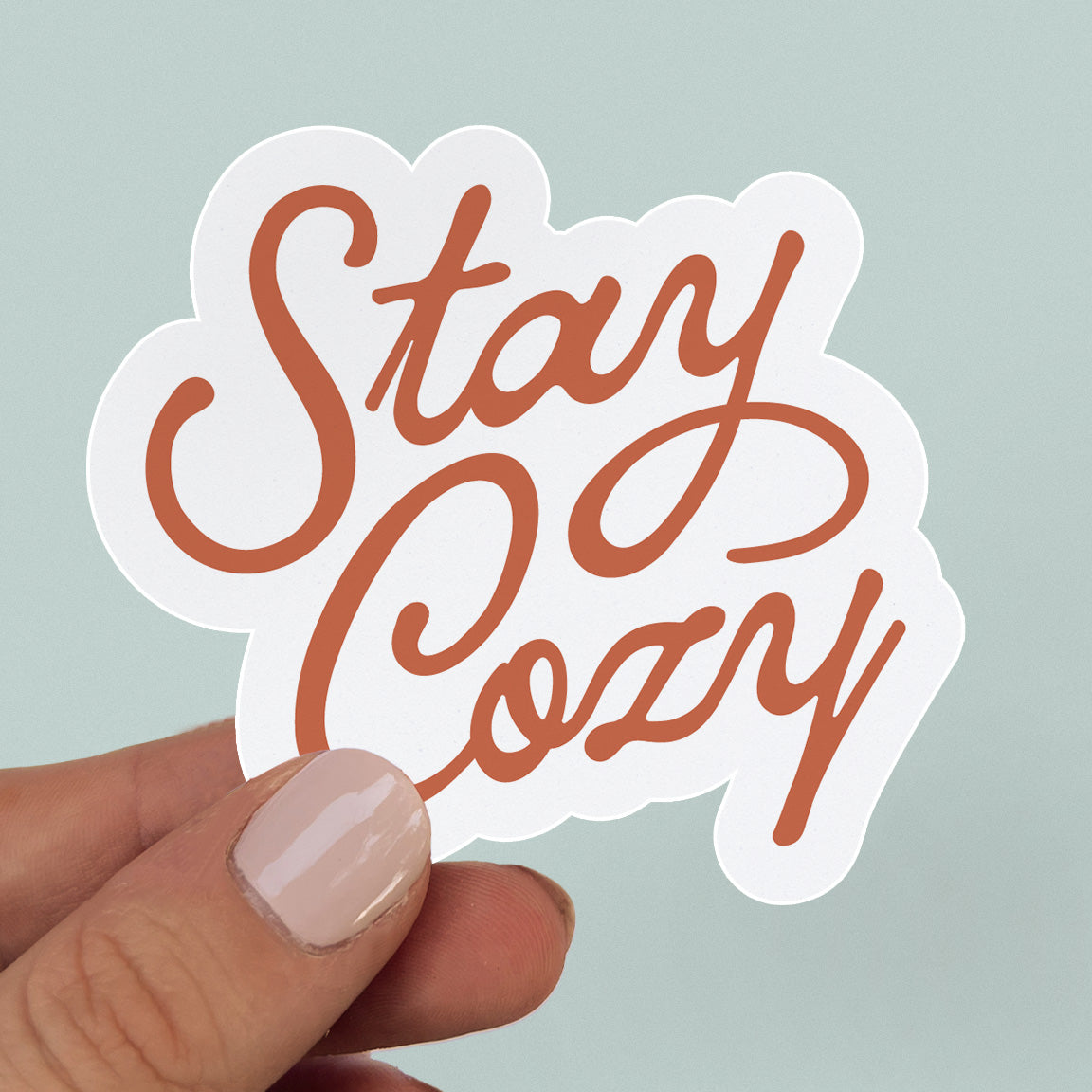 Sticker with quite "stay cozy" in red script lettering