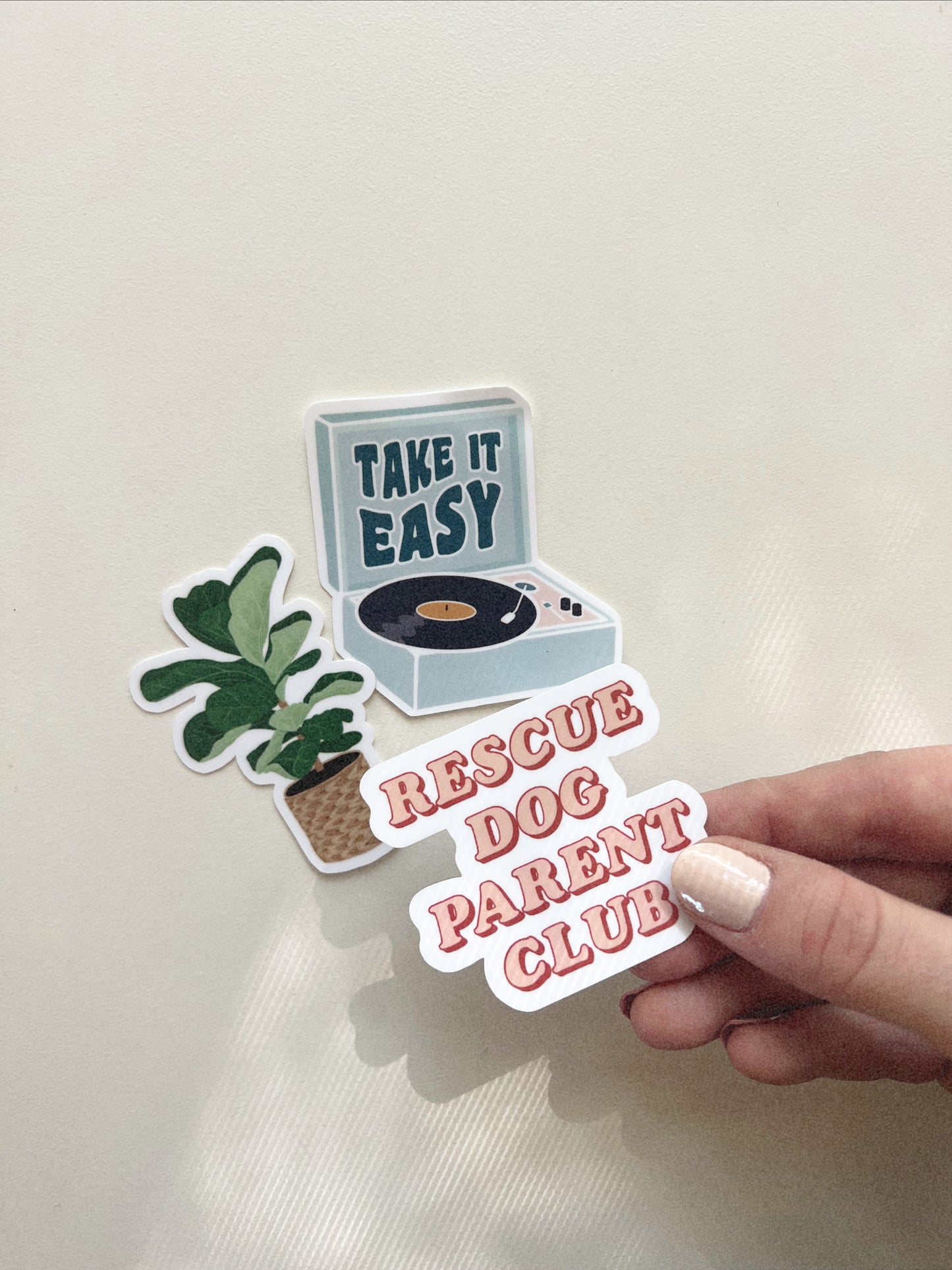 Rescue Dog Parent Club sticker held over Take It Easy Record Player Sticker and Fiddle Leaf Fig Sticker