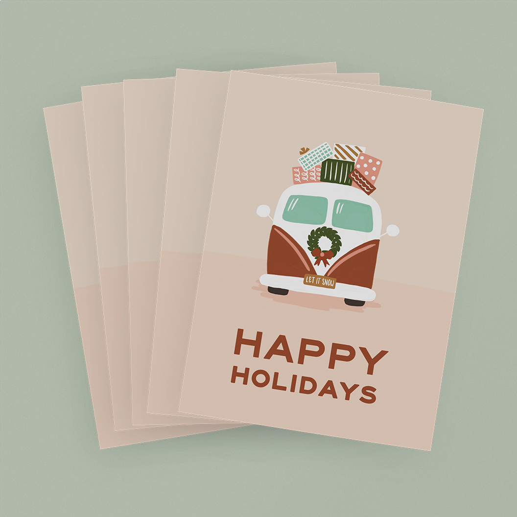 Stack of pink cards depicting a vintage-style van with presents on top and the message "Happy Holidays"