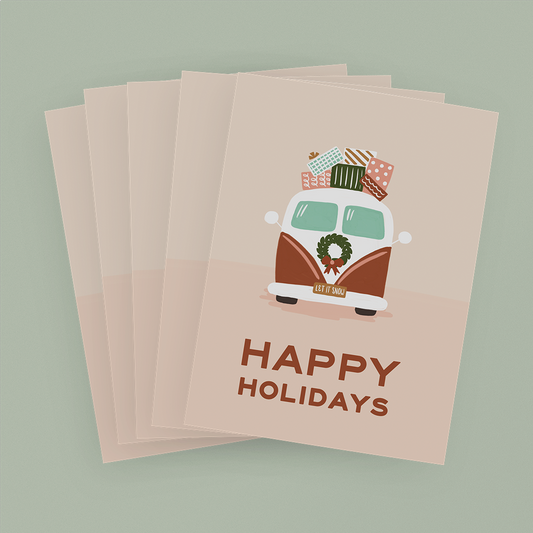 Stack of pink cards depicting a vintage-style van with presents on top and the message "Happy Holidays"