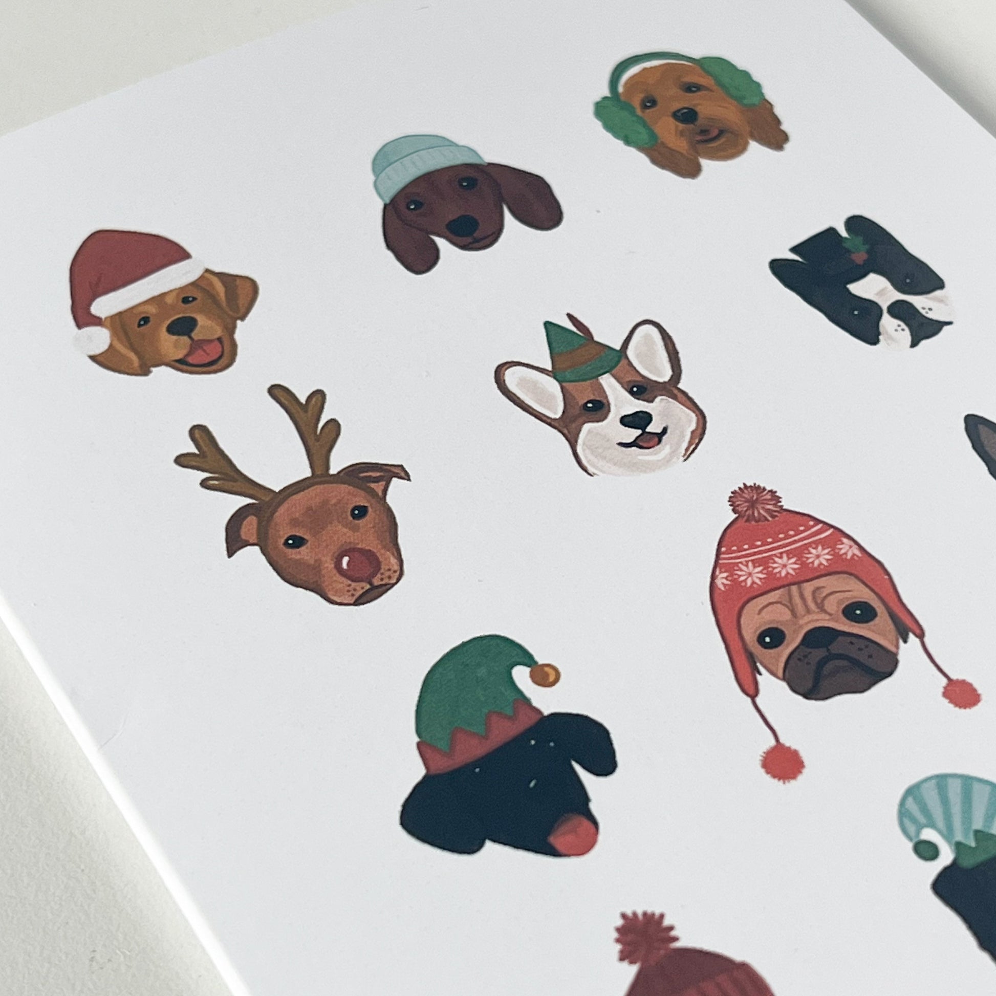 Close up of white card with 12 dogs, each in a different holiday hat