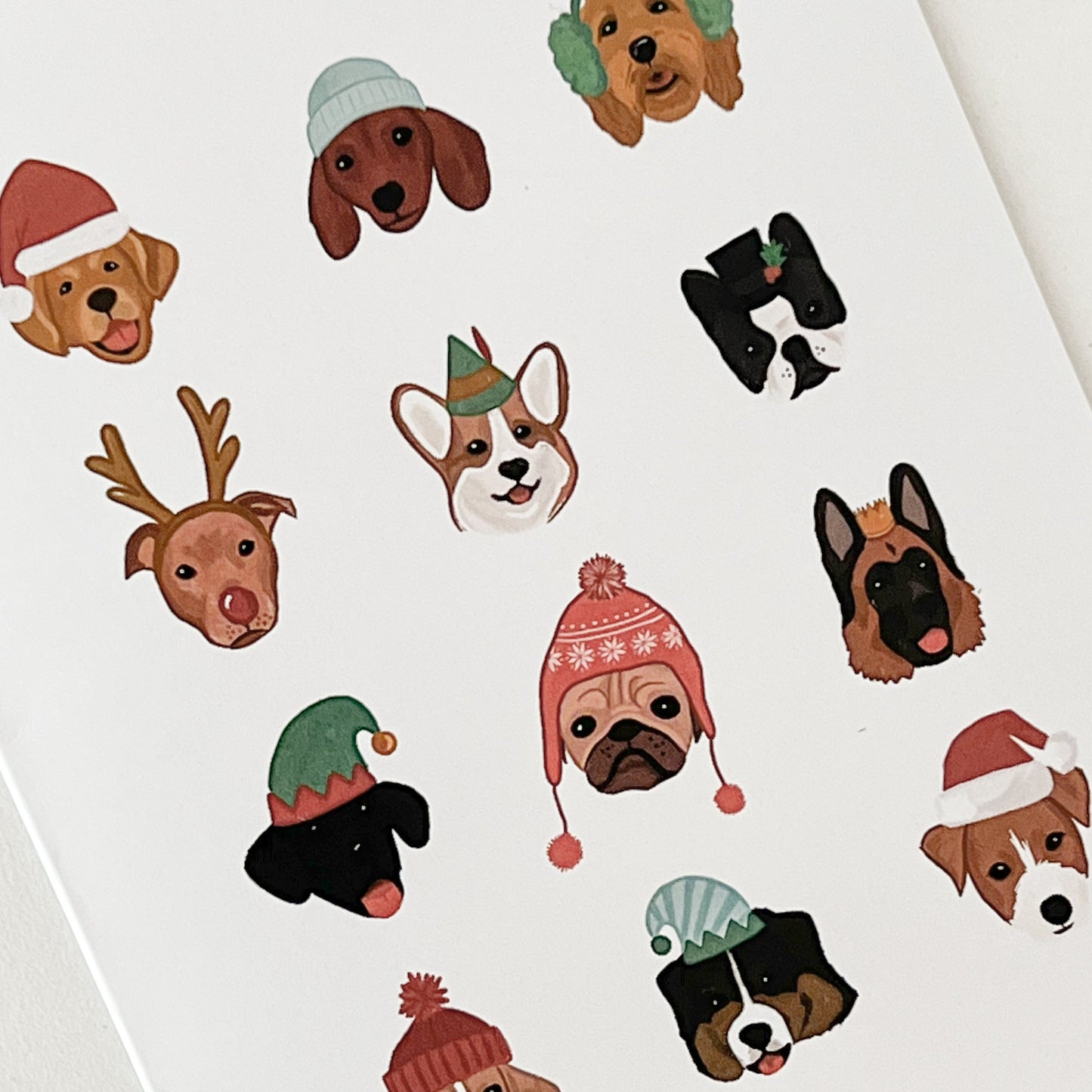 White card with 12 dogs, each in a different holiday hat