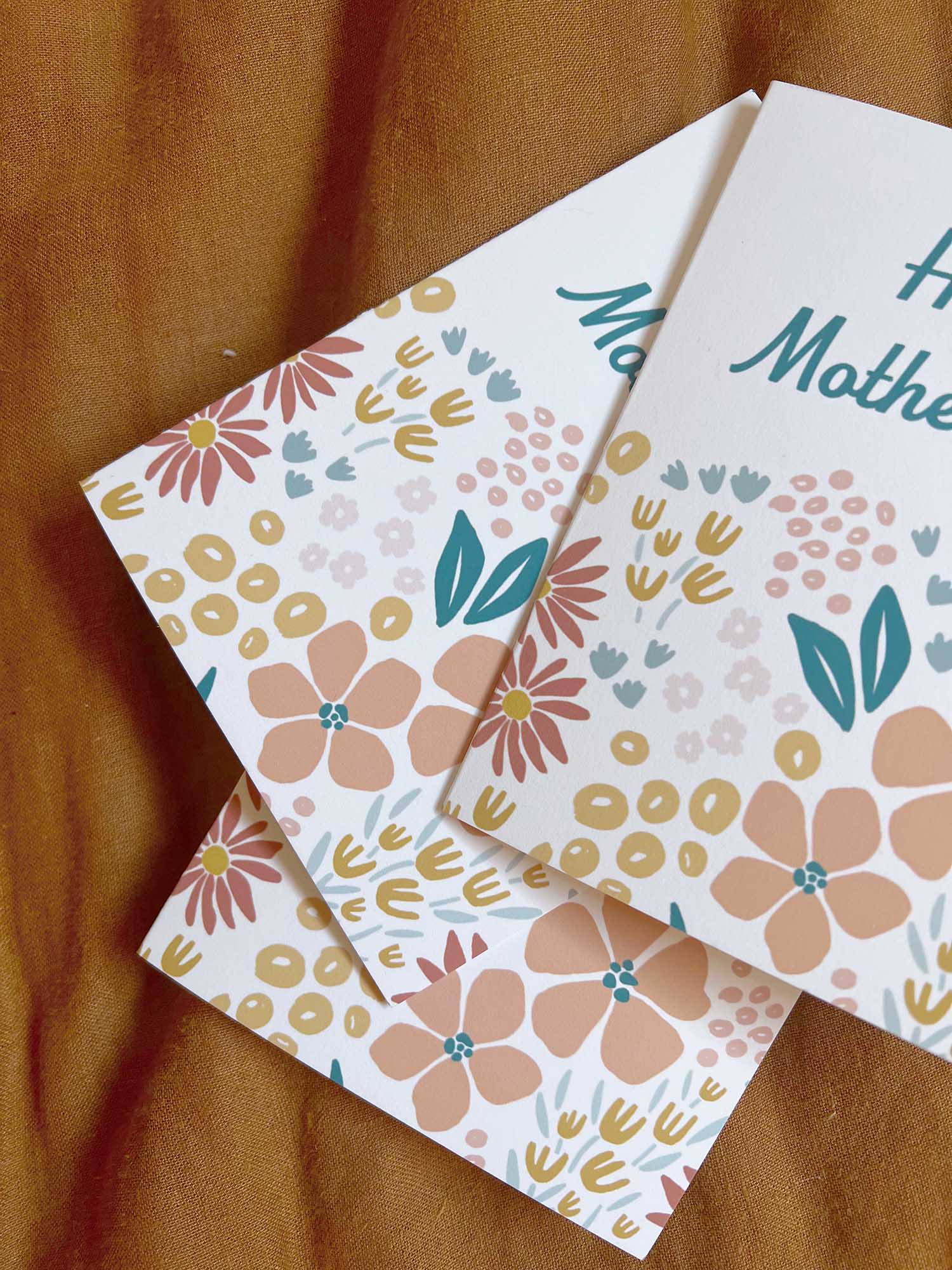 Multiple Floral Mother's Day cards on a rust fabric background
